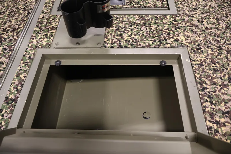 Slide: The Image of 2014 Lowe Roughneck 1756 boat storage compartment with camouflage flooring and cup holder. - 16