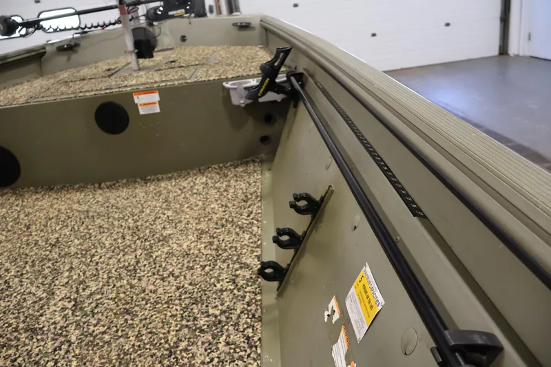 Slide: The Image of 2014 Lowe Roughneck 1756 boat interior with camouflage flooring and rod holders. - 18