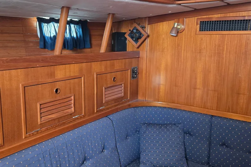 Slide: The Image of Cozy 1995 Contest 46/48 yacht interior with wooden paneling and blue cushioned seating. - 44