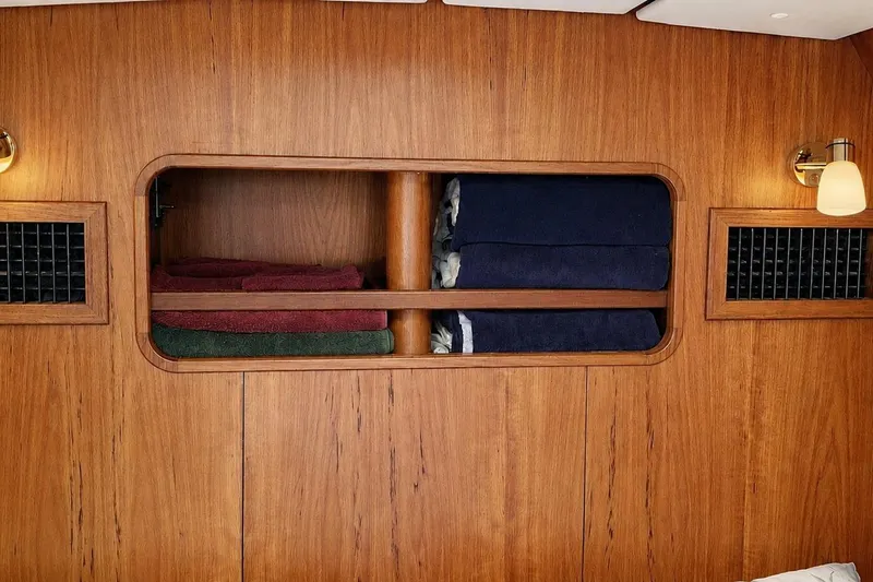 Slide: The Image of Wooden yacht interior with shelves holding folded towels, featuring warm lighting. Contest 46/48, 1996 model. - 34
