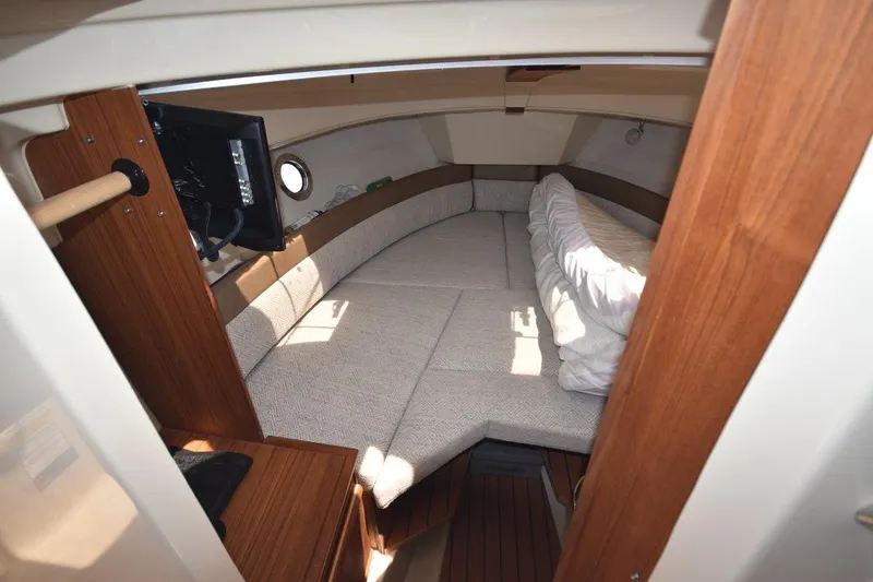 Slide: The Image of 2024 Ranger Tugs R-25 cabin interior with cozy bed and wooden accents. - 15