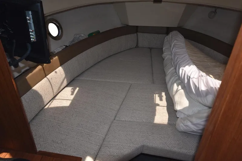 Slide: The Image of 2024 Ranger Tugs R-25 cabin interior with cozy bed and porthole window. - 16