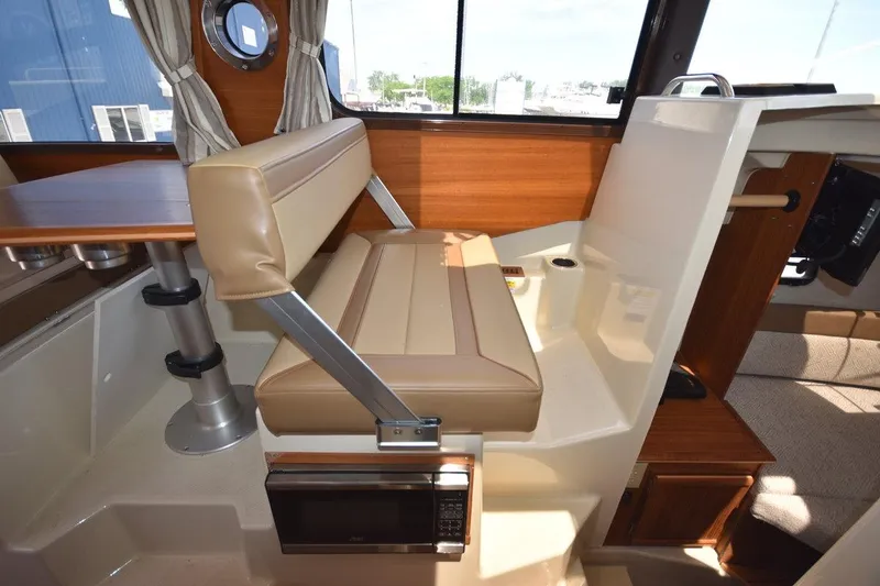 Slide: The Image of 2024 Ranger Tugs R-25 interior with beige seating and wooden accents. - 18