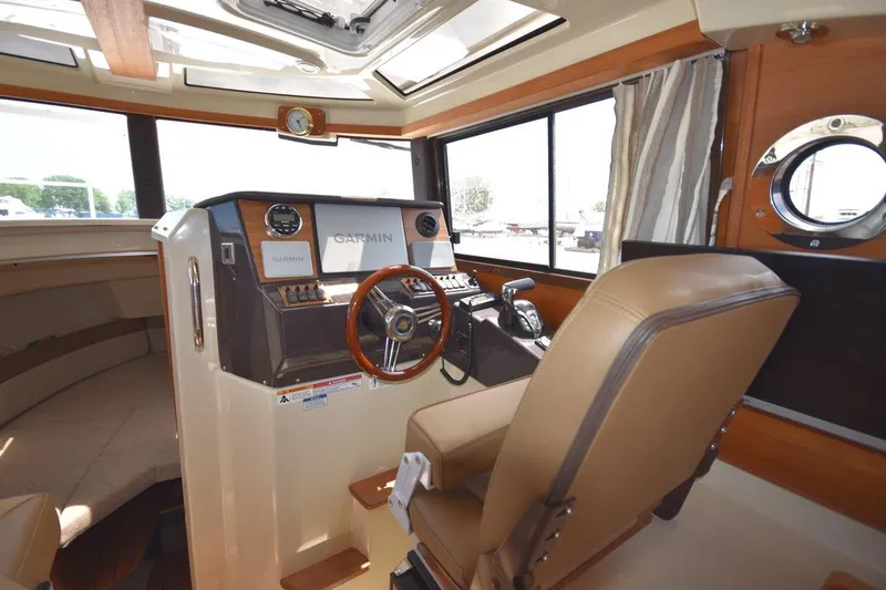 Slide: The Image of 2024 Ranger Tugs R-25 helm with Garmin navigation, featuring comfortable seating and modern controls. - 19