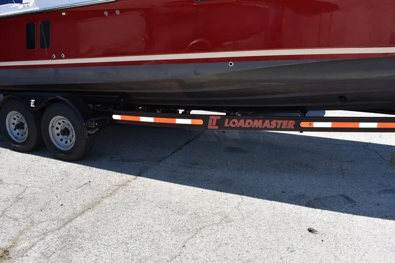 Slide: The Image of 2024 Ranger Tugs R-25 boat on Loadmaster trailer, red and black hull. - 30