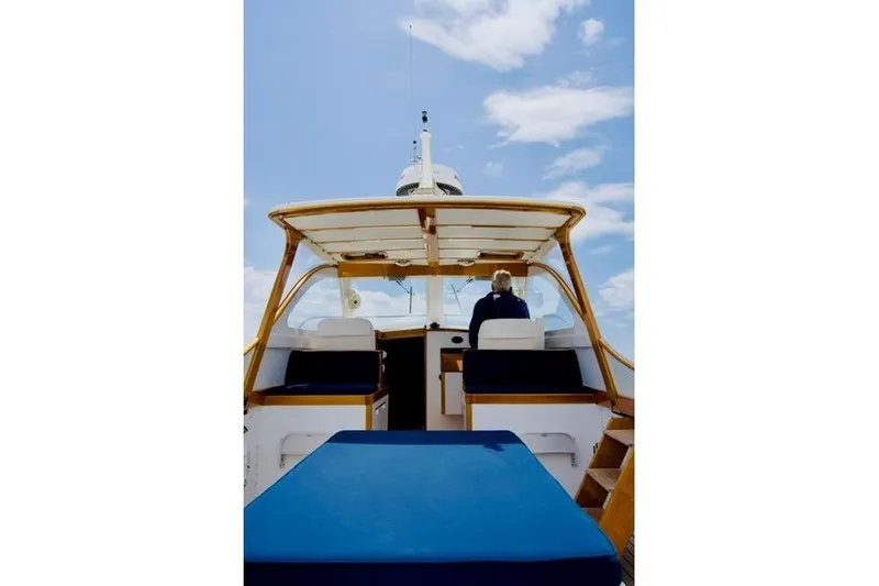 Slide: The Image of 2003 Lyman-Morse Monhegan 30 boat interior with blue seating under a clear sky. - 1