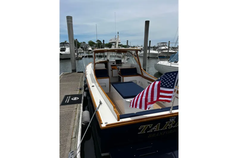 Slide: The Image of 2003 Lyman-Morse Monhegan 30 boat docked, featuring American flag and elegant wooden trim. - 8