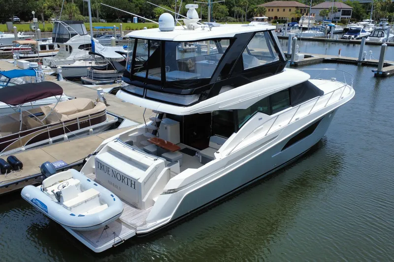 Slide: The Image of 2017 Tiara Yachts F53 Flybridge docked at marina with inflatable boat. - 2
