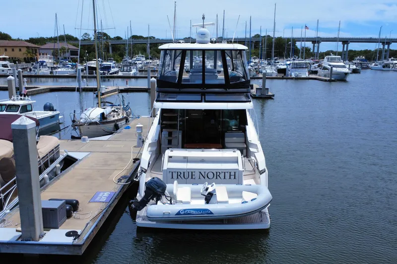 Slide: The Image of 2017 Tiara Yachts F53 Flybridge docked at marina, rear view with tender boat. - 4