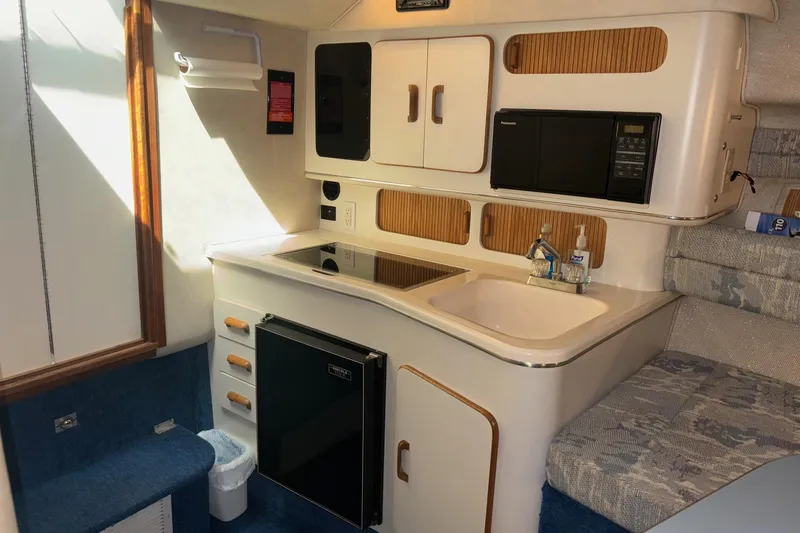 Slide: The Image of 1992 Sea Ray 300 Weekender boat interior with kitchenette, featuring sink, stove, and microwave. - 17
