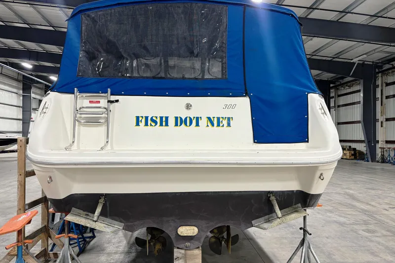 Slide: The Image of 1992 Sea Ray 300 Weekender boat with blue cover in a warehouse. - 5