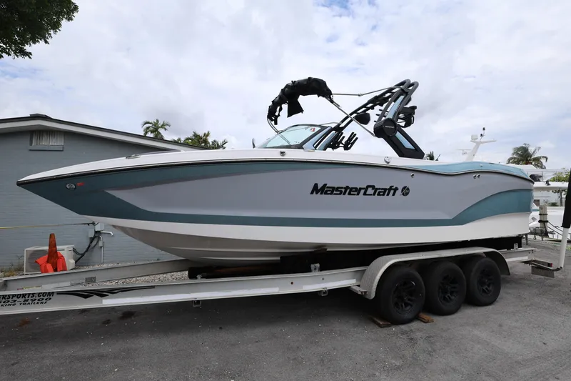 The Image of 2023 MasterCraft X24 boat on trailer, sleek design, parked outdoors. - 0