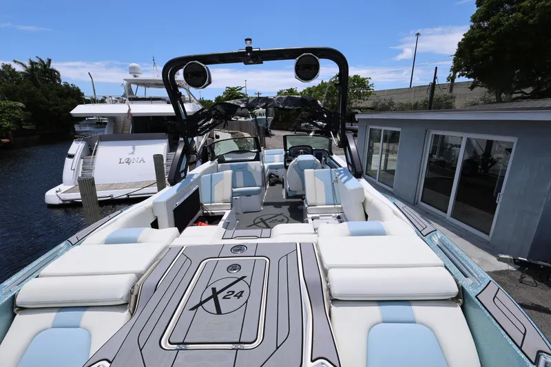 Slide: The Image of 2023 MasterCraft X24 boat with luxurious seating and sleek design docked by the water. - 13
