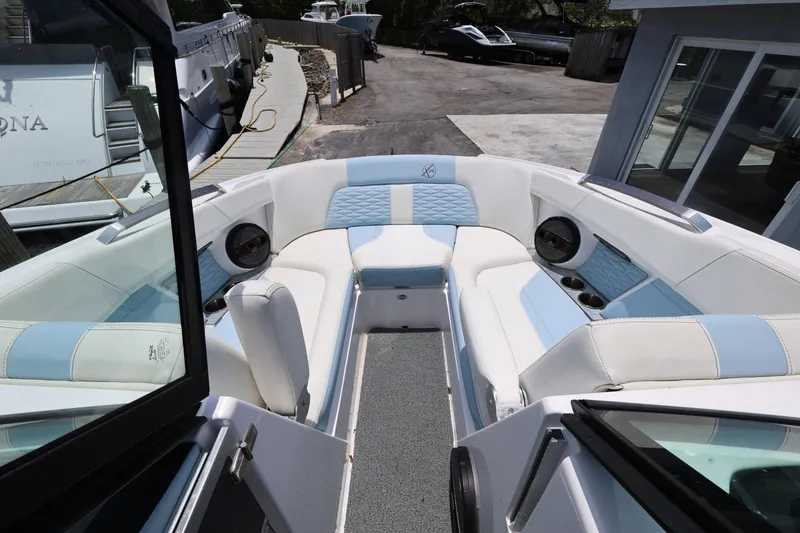 Slide: The Image of 2023 MasterCraft X24 boat interior with white and blue seating, docked at marina. - 20