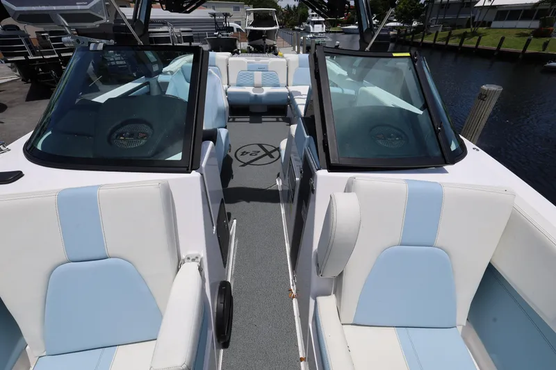 Slide: The Image of 2023 MasterCraft X24 boat interior with blue and white seating, docked by a canal. - 22
