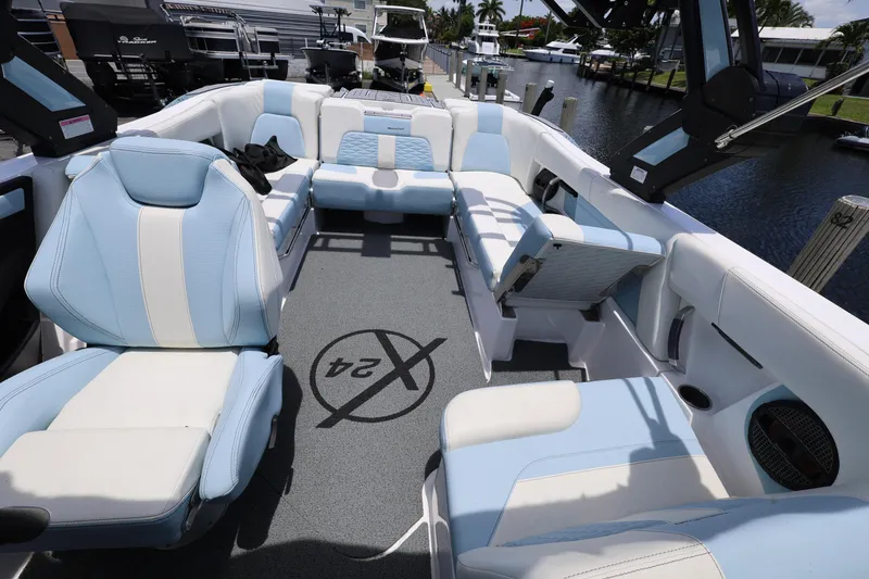Slide: The Image of 2023 MasterCraft X24 boat interior with blue and white seating, docked by a canal. - 25