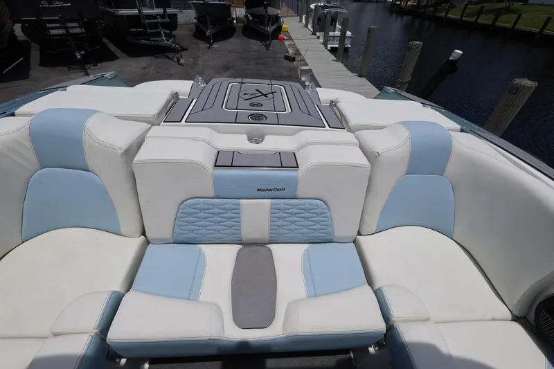 Slide: The Image of 2023 MasterCraft X24 boat interior with white and blue seating at a dock. - 27
