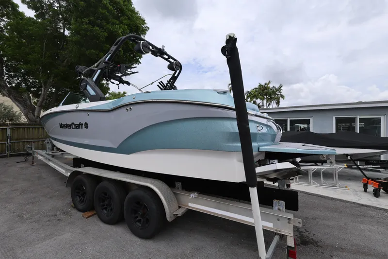 Slide: The Image of 2023 MasterCraft X24 boat on trailer, parked outdoors near trees and buildings. - 3
