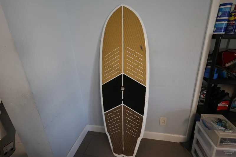 Slide: The Image of 2023 MasterCraft X24 surfboard with a tri-color design, leaning against a wall indoors. - 31