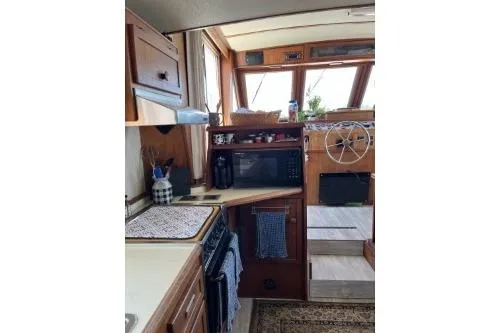 Slide: The Image of 1983 Uniflite Cabin Cruiser interior with kitchen and helm, featuring wood cabinetry and appliances. - 10