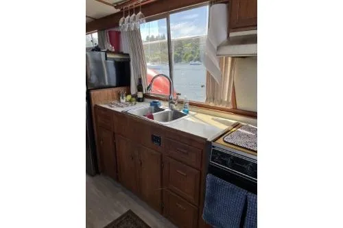 Slide: The Image of 1983 Uniflite Cabin Cruiser kitchen with wooden cabinets and scenic window view. - 11