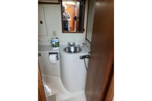 Slide: The Image of 1983 Uniflite Cabin Cruiser bathroom with sink, mirror, and toilet paper holder. - 14