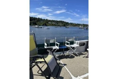 Slide: The Image of 1983 Uniflite Cabin Cruiser deck with chairs overlooking a scenic waterfront. - 18