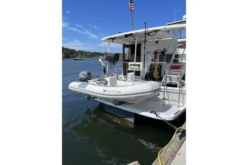 Slide: The Image of 1983 Uniflite Cabin Cruiser docked with inflatable boat, American flag, and scenic water view. - 3