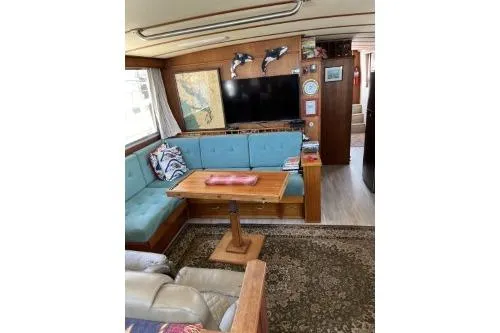 Slide: The Image of 1983 Uniflite Cabin Cruiser interior with blue seating, wooden table, and wall-mounted TV. - 7