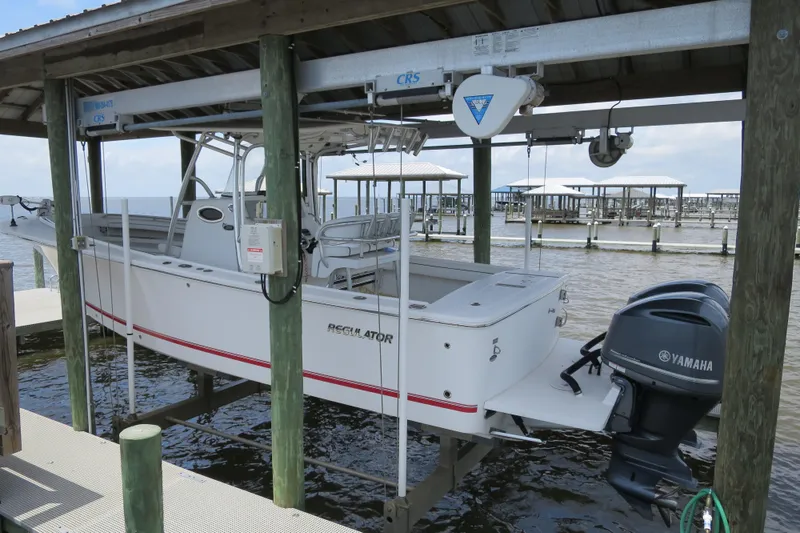 Slide: The Image of 2016 Regulator 28 boat with Yamaha engines on a lift at a marina. - 1