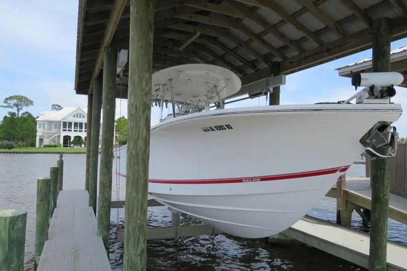 Slide: The Image of 2016 Regulator 28 boat docked under a wooden shelter by the water. - 3