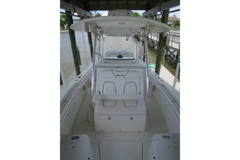Slide: The Image of 2016 Regulator 28 boat interior with seating and helm, docked by the water. - 5
