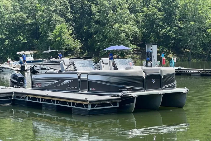 Slide: The Image of 2017 Premier 270 Super Sport pontoon boat docked on a serene lake. - 2