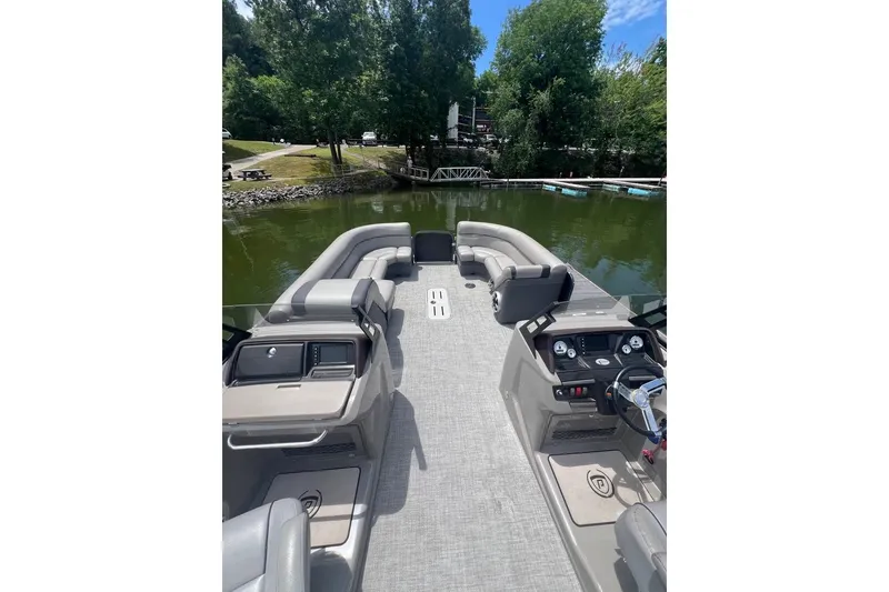 Slide: The Image of 2017 Premier 270 Super Sport pontoon boat interior with seating and control panel on a lake. - 6