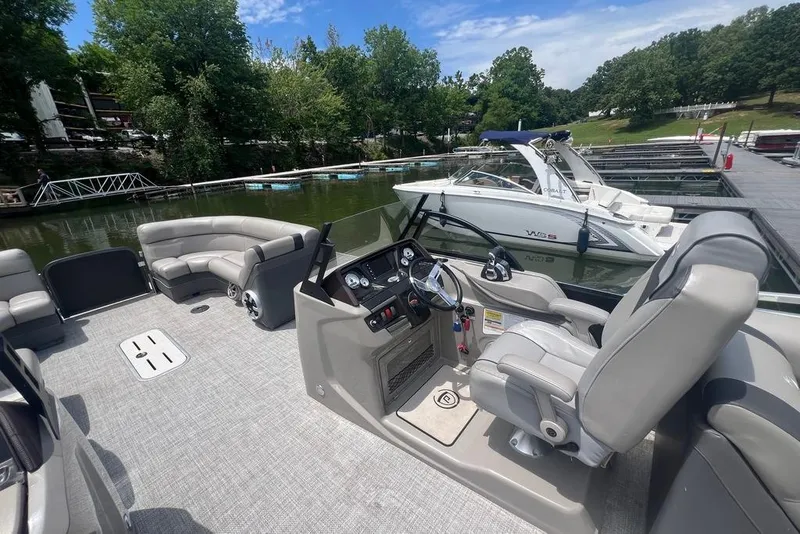 Slide: The Image of 2017 Premier 270 Super Sport pontoon boat interior with helm and seating, docked by a lake. - 8