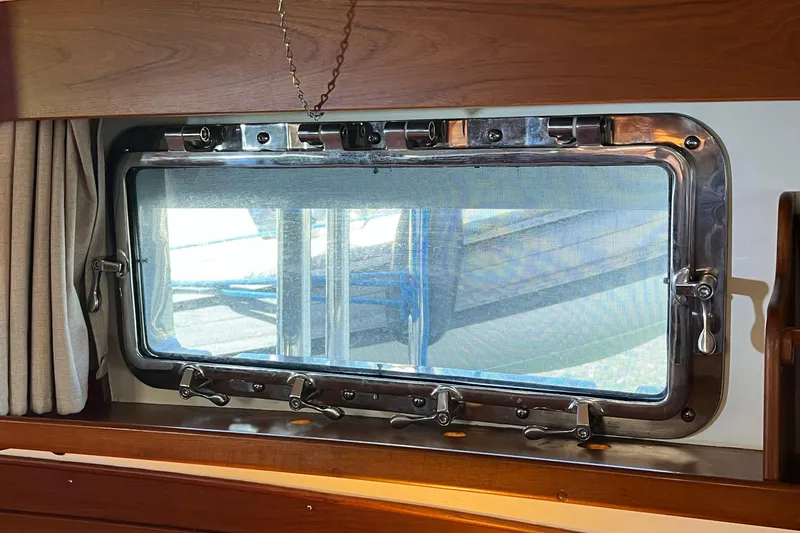Slide: The Image of Porthole window on 1991 Grand Banks 42 Motoryacht, featuring polished metal frame and curtain. - 22