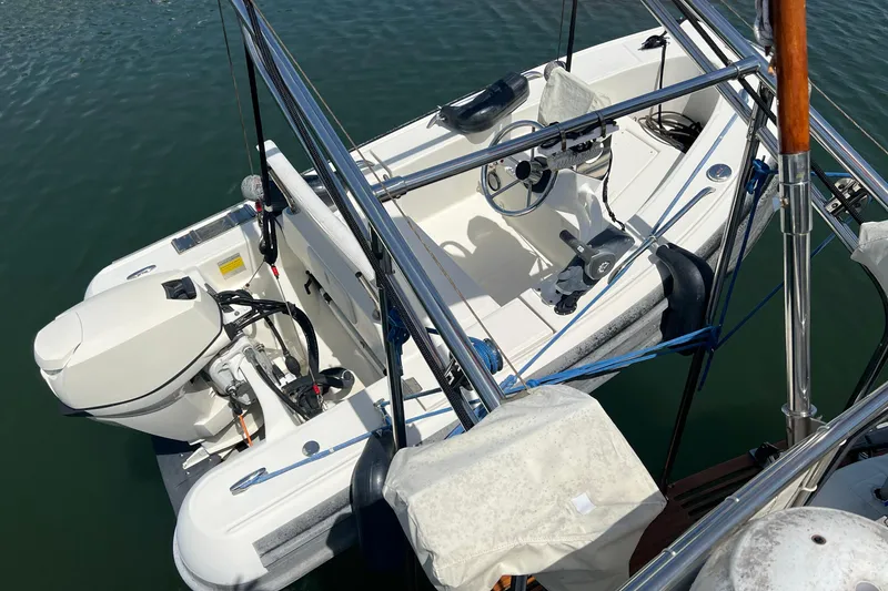 Slide: The Image of 1991 Grand Banks 42 Motoryacht with attached dinghy and outboard motor on calm water. - 33