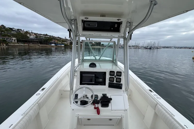 Slide: The Image of 2007 Regulator 26 Forward Seating boat interior with steering console, docked in a calm marina. - 10