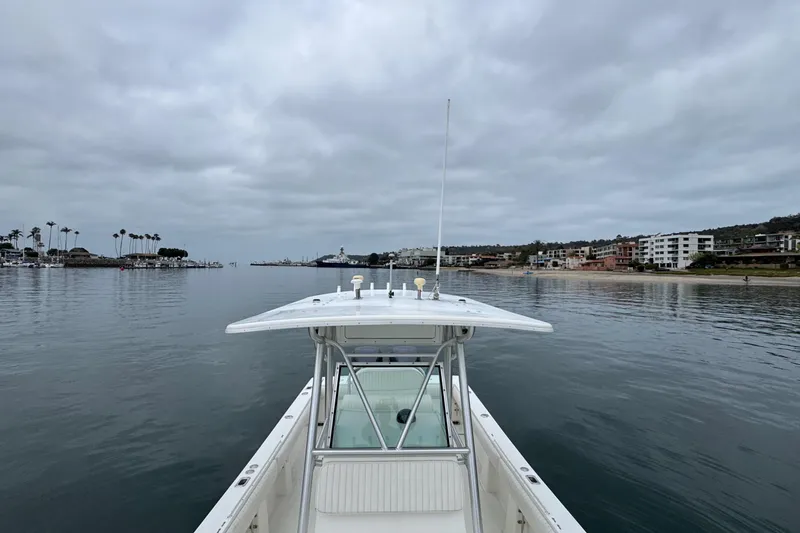 Slide: The Image of 2007 Regulator 26 Forward Seating boat on calm water near coastal buildings under cloudy sky. - 17
