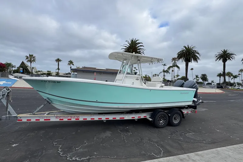 Slide: The Image of 2007 Regulator 26 Forward Seating boat on trailer, parked near palm trees under cloudy sky. - 22