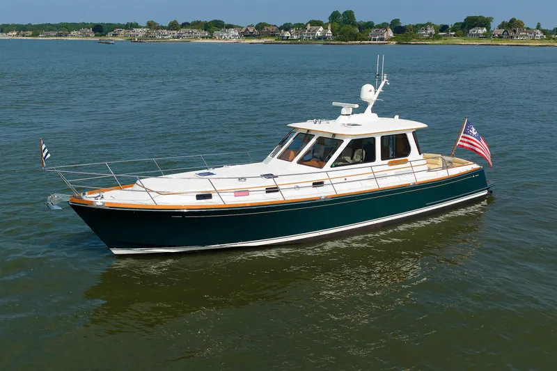Slide: The Image of Alden 52 Salon Express 2008 yacht cruising on calm waters near a coastal town. - 57