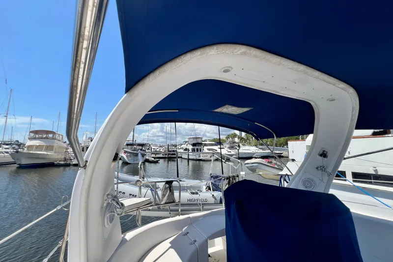 Slide: The Image of 1999 Hunter 380 sailboat docked at marina, featuring blue canopy and scenic harbor view. - 24