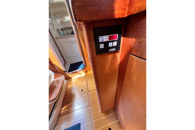 Slide: The Image of Interior of a 1999 Hunter 380 sailboat, featuring wooden paneling and control panel. - 46