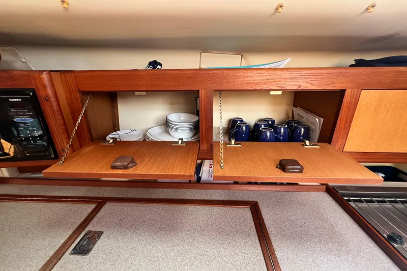 Slide: The Image of Wooden cabinets in a 1999 Hunter 380 yacht, storing dishes and mugs. - 47