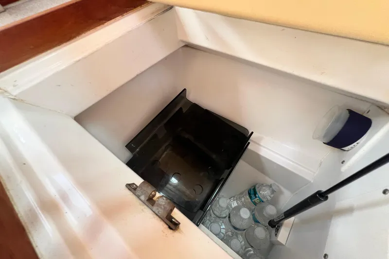 Slide: The Image of Storage compartment in a 1999 Hunter 380 sailboat, containing water bottles and a black tray. - 52