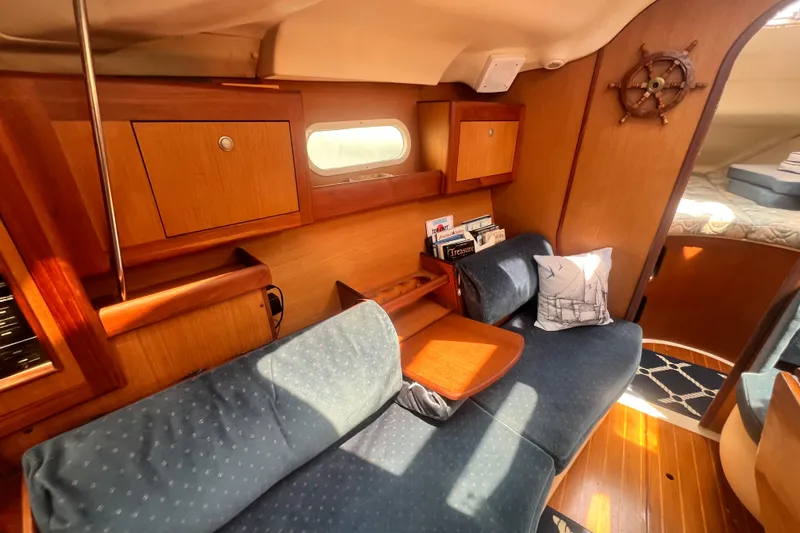 Slide: The Image of Cozy interior of a 1999 Hunter 380 sailboat with wooden cabinetry and blue seating. - 54