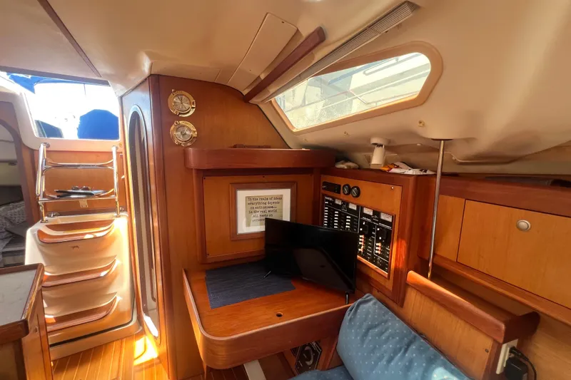 Slide: The Image of Interior of a 1999 Hunter 380 sailboat with wooden cabinetry and navigation equipment. - 55