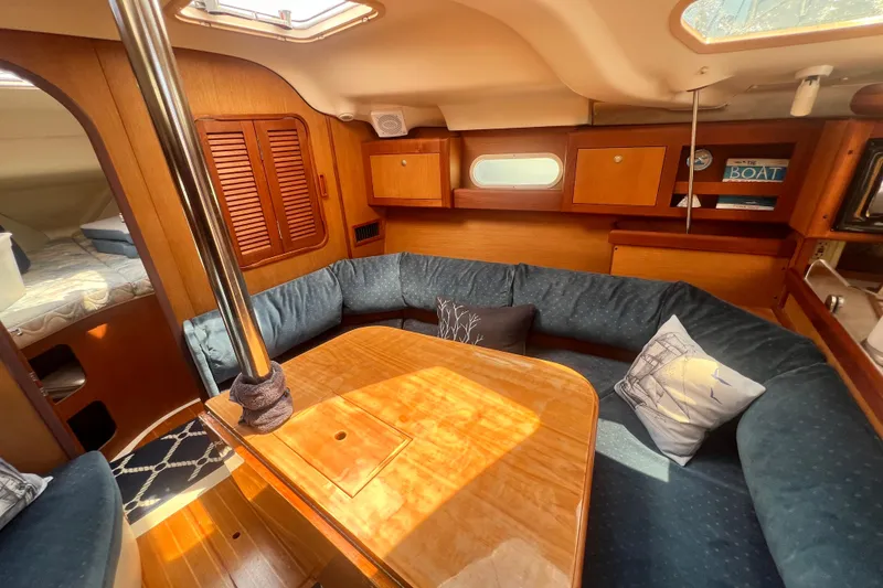 Slide: The Image of Cozy interior of a 1999 Hunter 380 sailboat with wooden furnishings and blue seating. - 58
