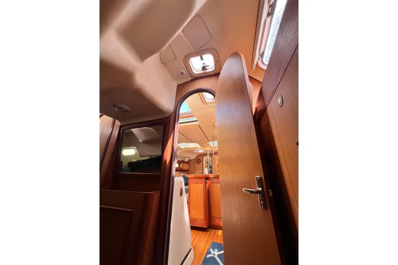 Slide: The Image of Interior view of a 1999 Hunter 380 sailboat, featuring wooden cabinetry and open door. - 77