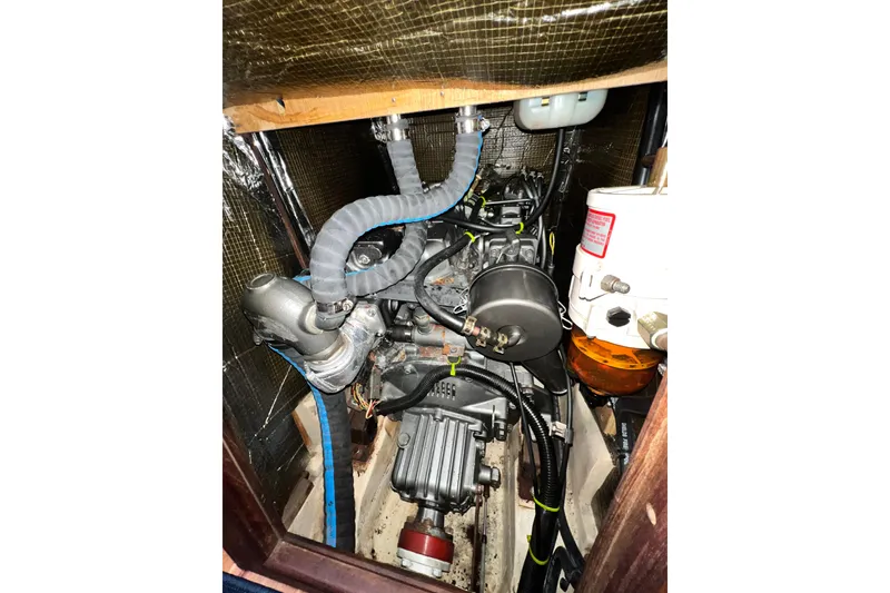 Slide: The Image of Engine compartment of a 1999 Hunter 380 sailboat, showcasing mechanical components and hoses. - 79